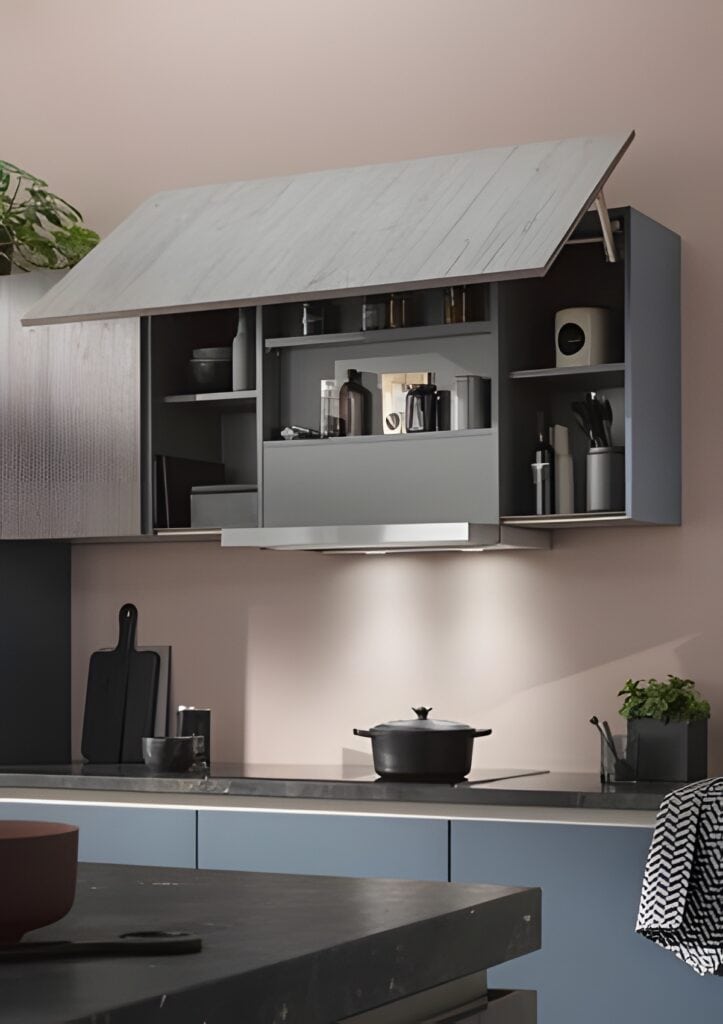 Modern kitchen with an open overhead cabinet, displaying various kitchen items including utensils and containers. A pot is on the stove, and a small plant is on the counter. The space features an integrate lift system for effortless access to stored items. verhead cabinet, displaying various kitchen items including utensils and containers. A pot is on the stove, and a small plant is on the counter. The space features an integrate lift system for effortless access to stored items.
