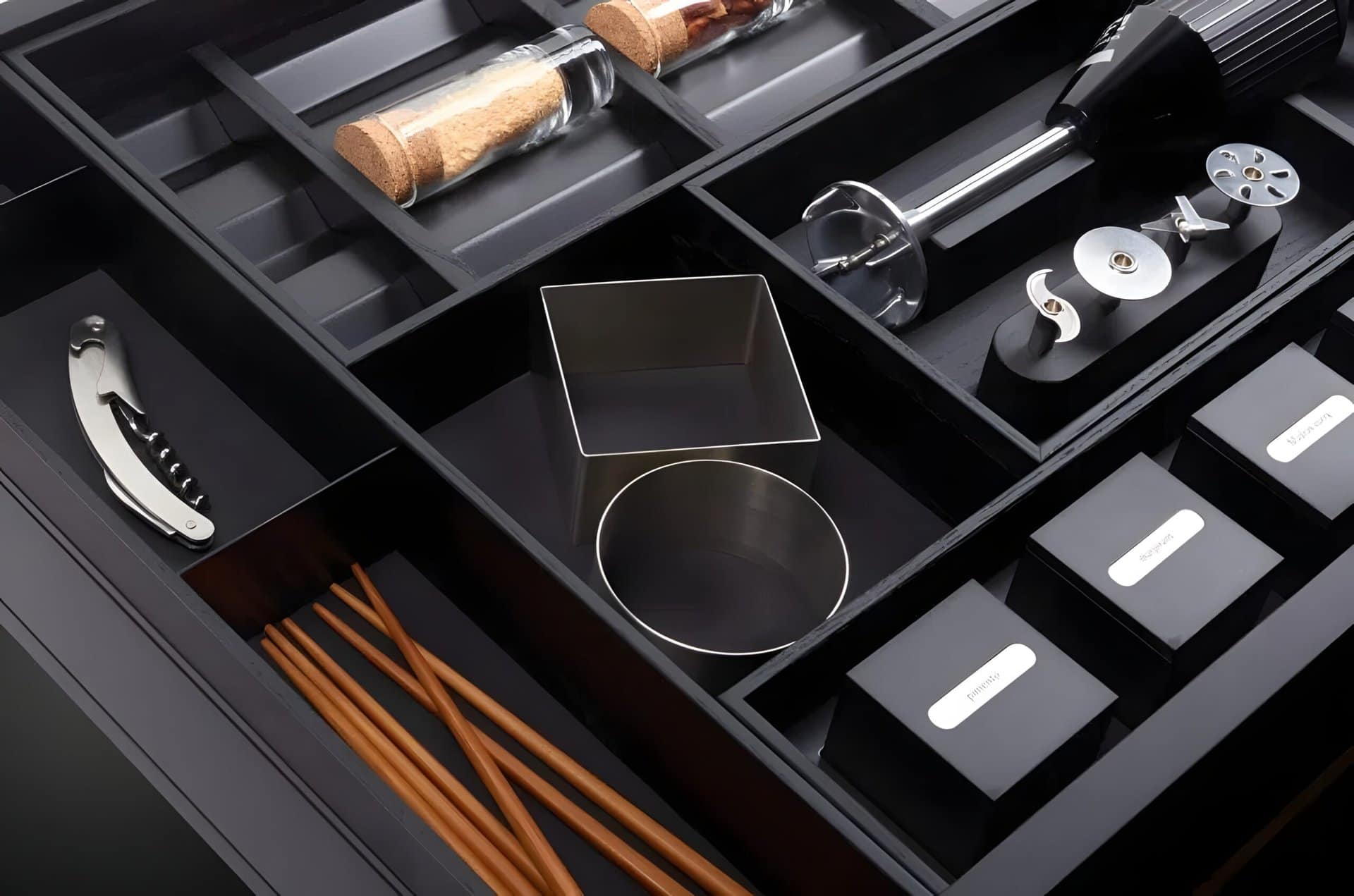 An organized Bauformat Accessories wine cabinet accessory drawer with various tools such as a corkscrew, wine stopper, and aerator neatly stored in compartments.