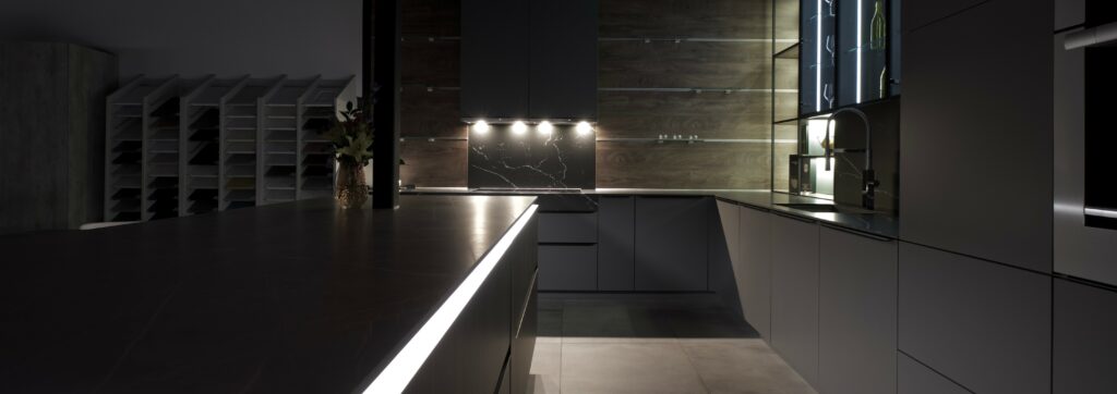 Modern kitchen with sleek design featuring dark tones and creating a layered approach to kitchen lighting.